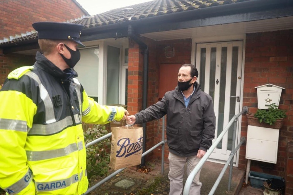 Garda handing a bag of shopping to a man.