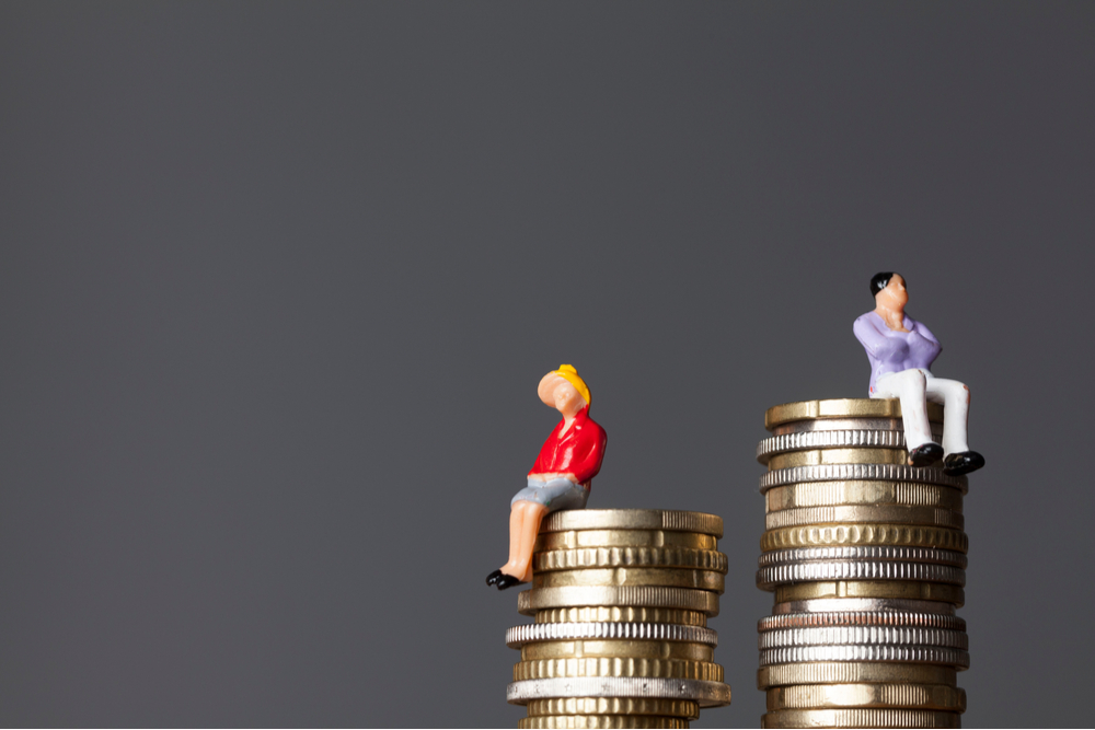 Man sitting on a higher stack of coins than a woman.