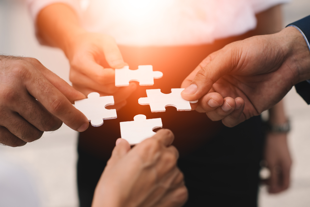 Group of people holding pieces of a jigsaw puzzle.