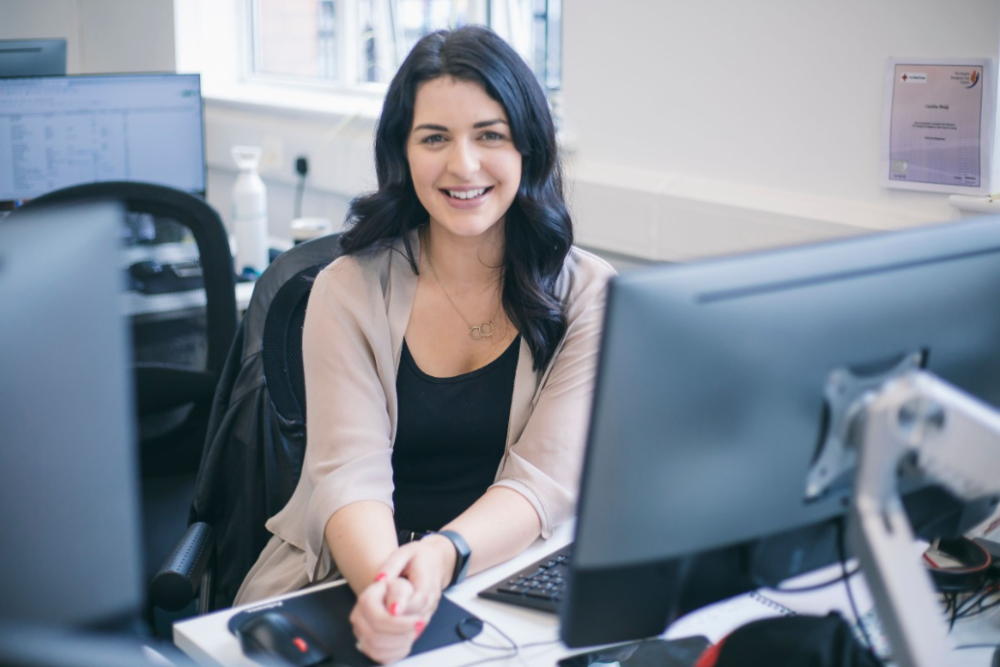 Young woman with dark hair sitting at a desk.