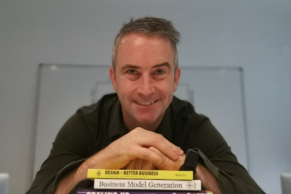 Man in green shirt leaning on a pile of books.