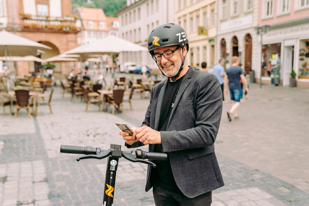 Man wearing helmet using an electric scooter.