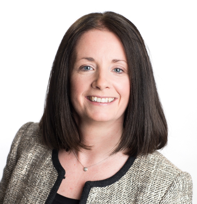 Dark-haired woman in grey business suit.