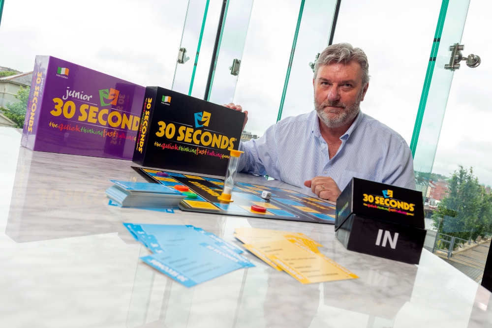 Man in blue shirt surrounded by board games 30 Seconds.