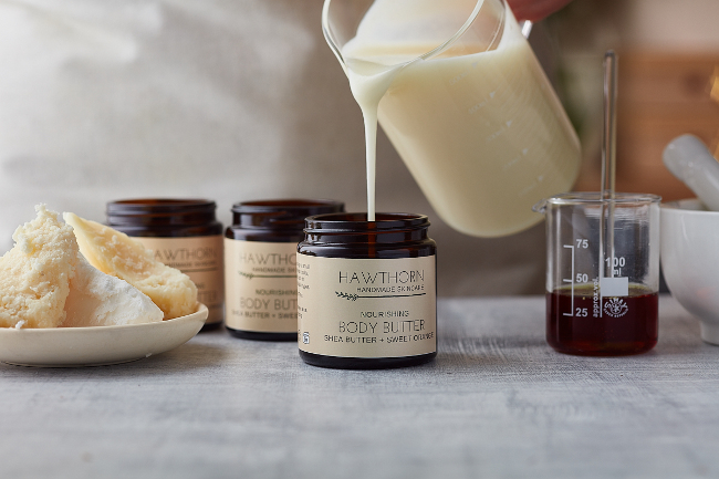 Pouring body butter into a jar.