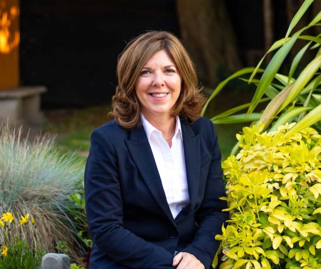 Woman in navy jacket and white blouse.