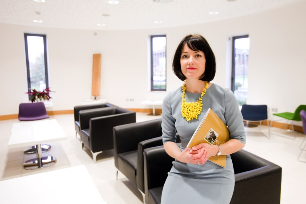 Dark-haired woman in grey dress.