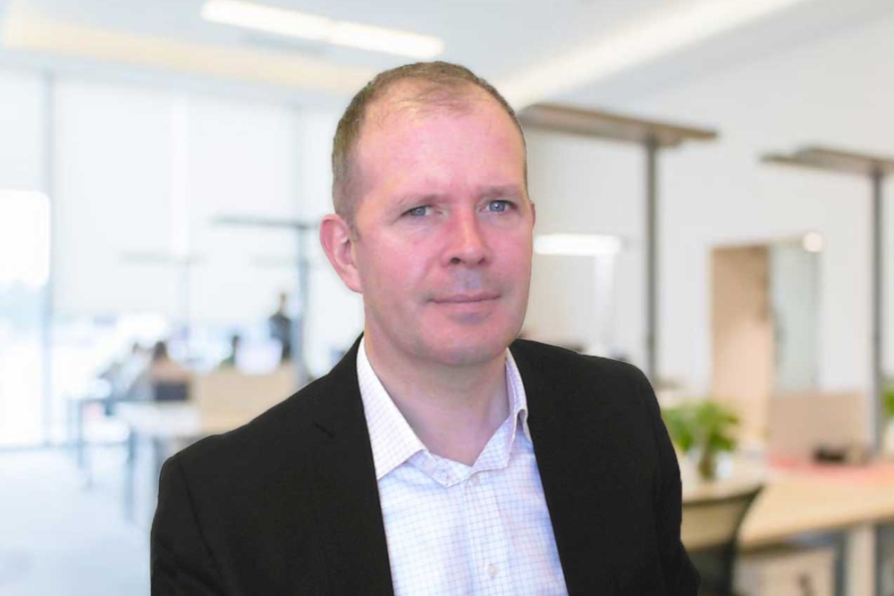 Man wearing white shirt and black jacket in an office.