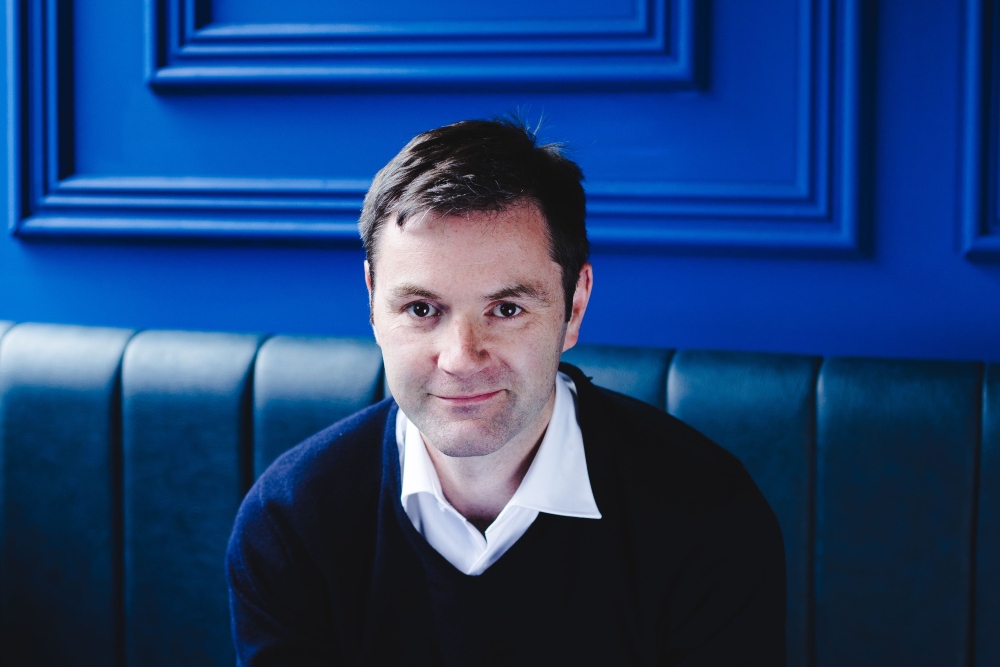 Man sitting on seat in front of blue wall.