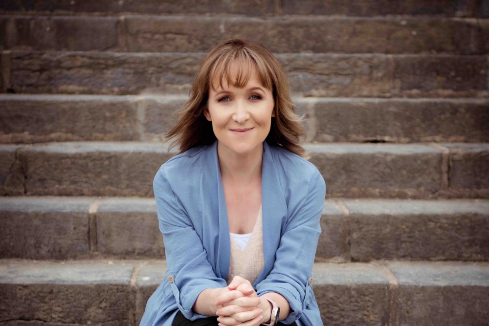 Young red-haired woman sitting on steps.