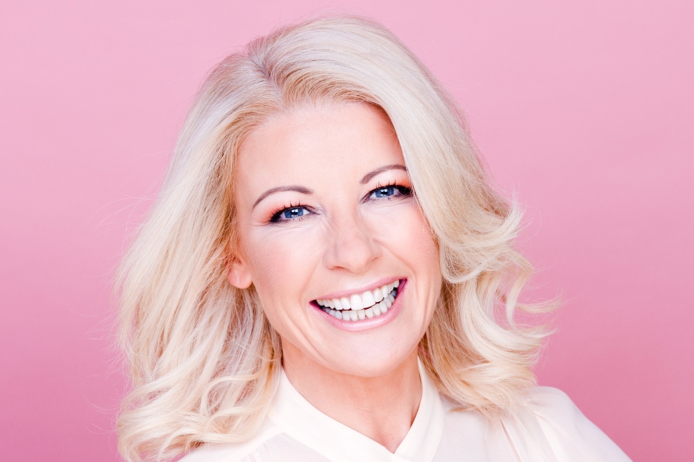 Smiling woman with blonde-hair, white blouse.