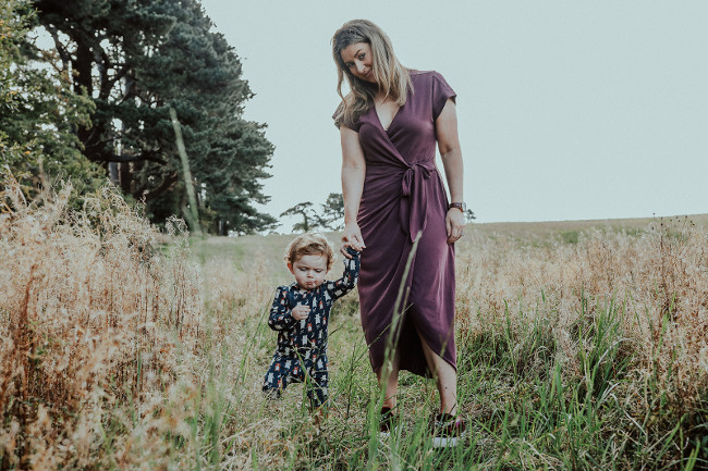 Mother walking her young son in a field.