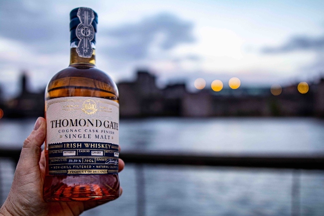 Holding a bottle of whiskey in front of King John's Castle in Limerick