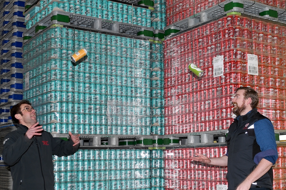 Two young men tossing cans of beer in the air.