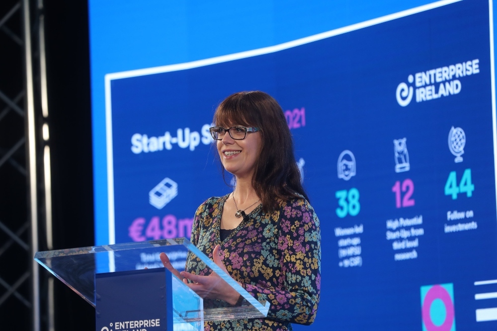 Dark-haired woman speaking from a podium.