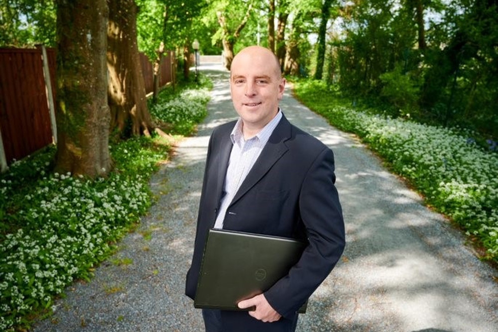 Man in suit holding a laptop.