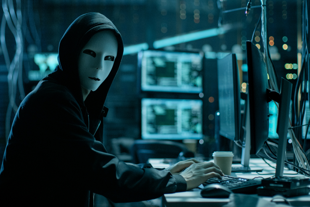 Masked hacker in a computer room.