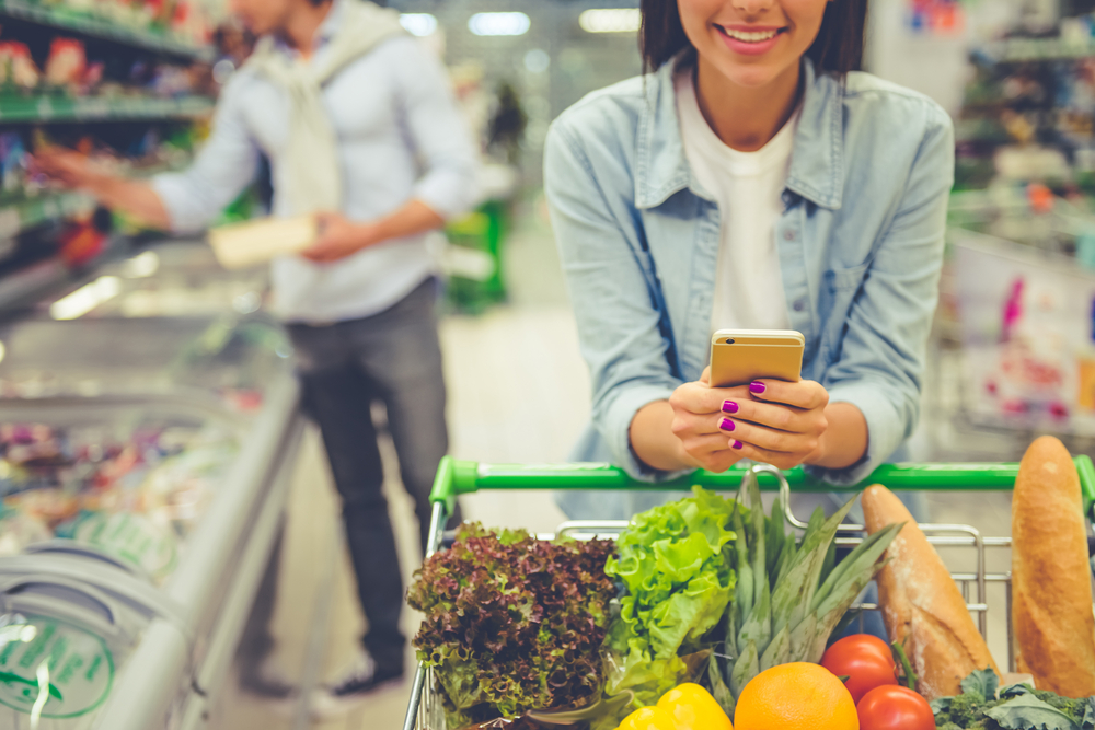 Woman using phone while shopping in a grocery.