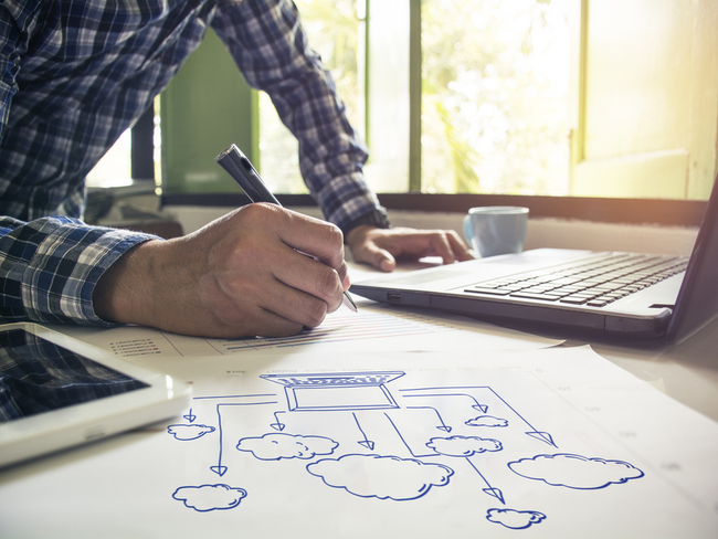 Man writing out a cloud architecture.