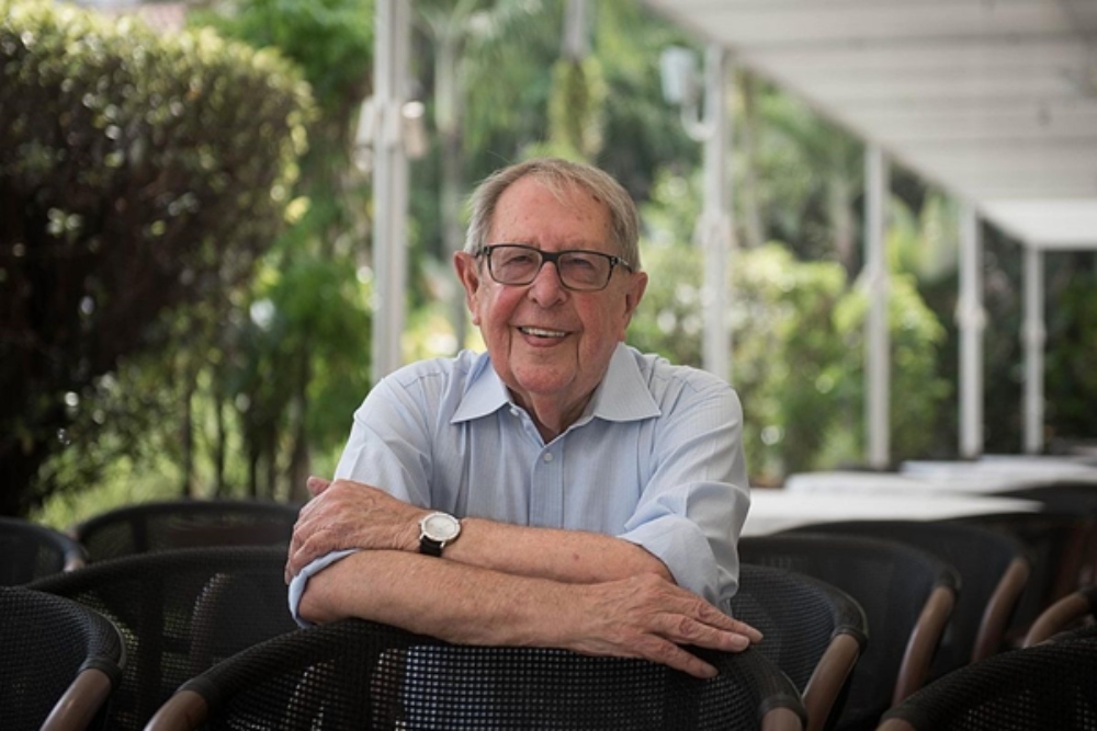 Man in glasses leaning on a chair.