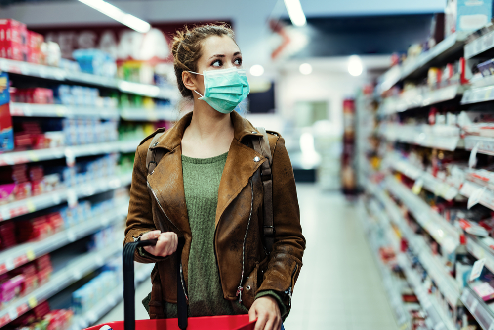 Young woman shopping while wearing a face mask in pandemic.