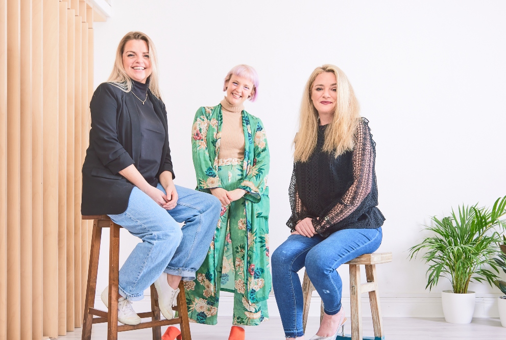 Three women sitting on stools.