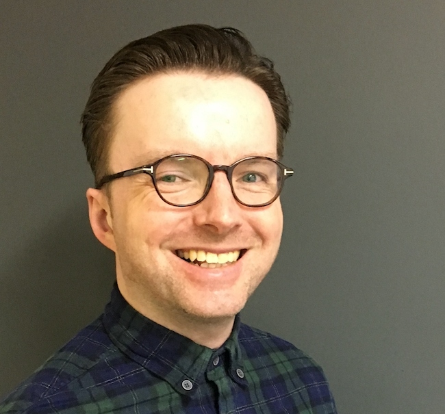 Dark-haired man in glasses and check shirt.