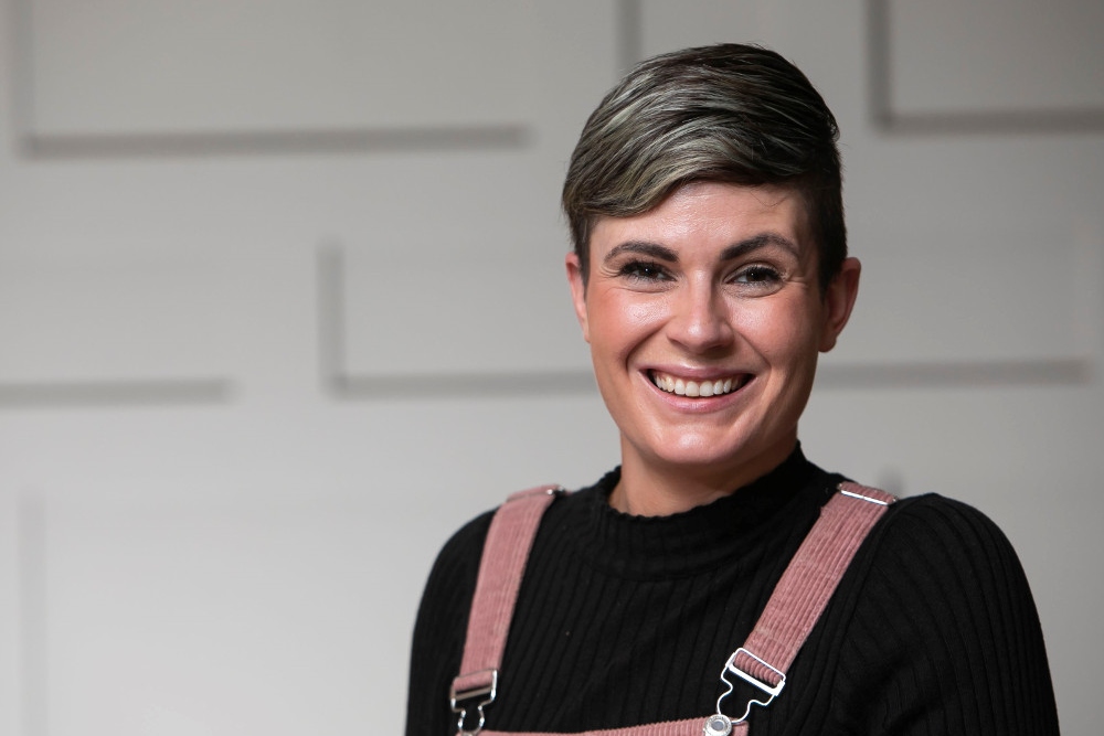 Woman in black top with pink dungarees.