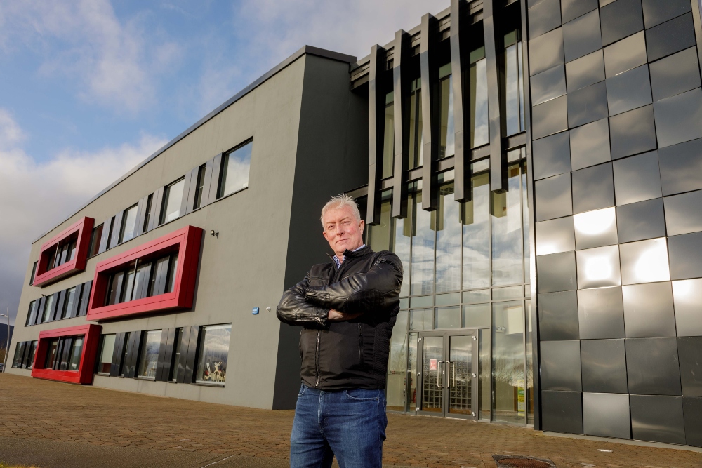 Man in leather jacket standing in front of building.