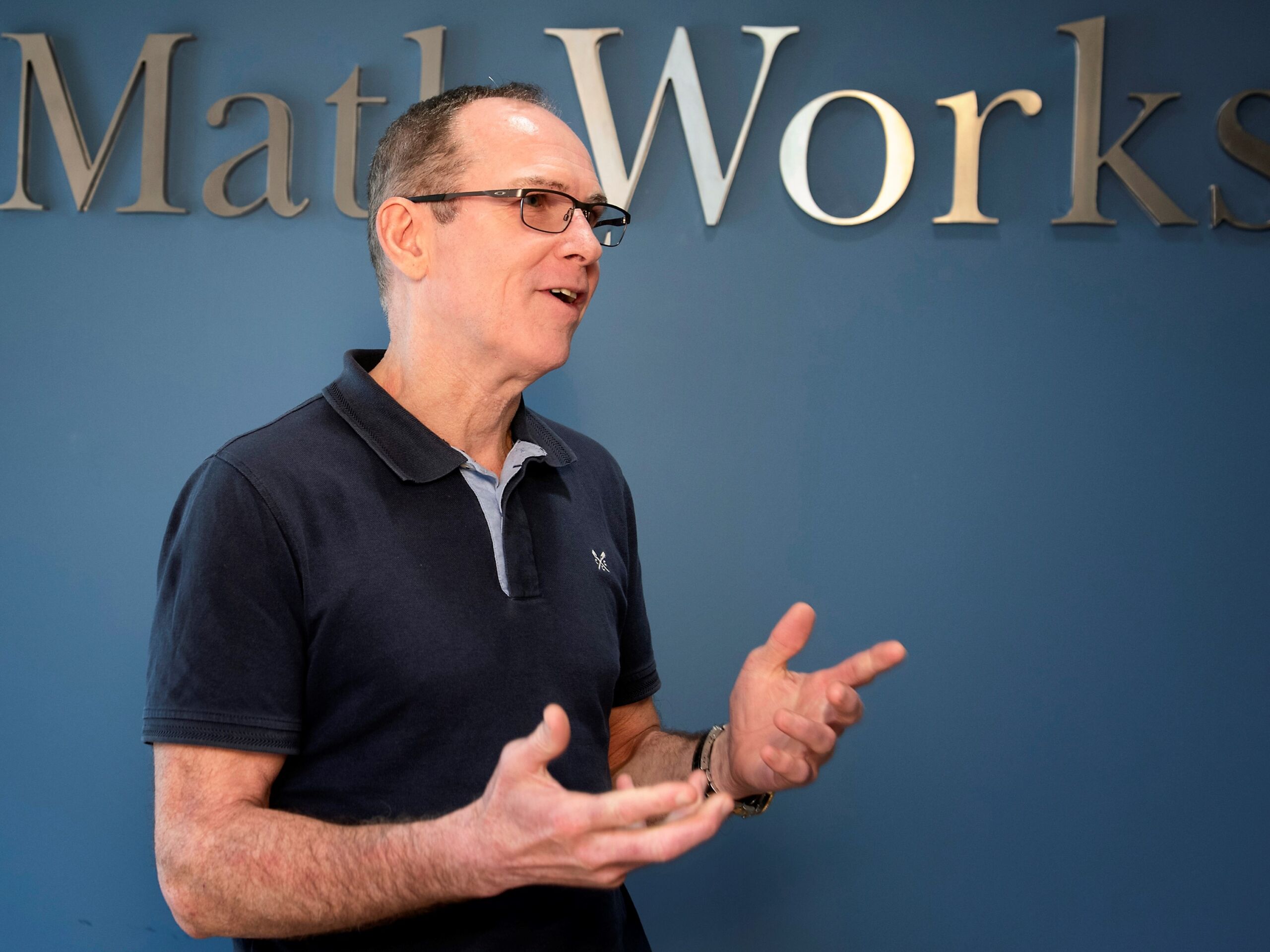 Man in black t-shirt under a sign saying MathWorks.