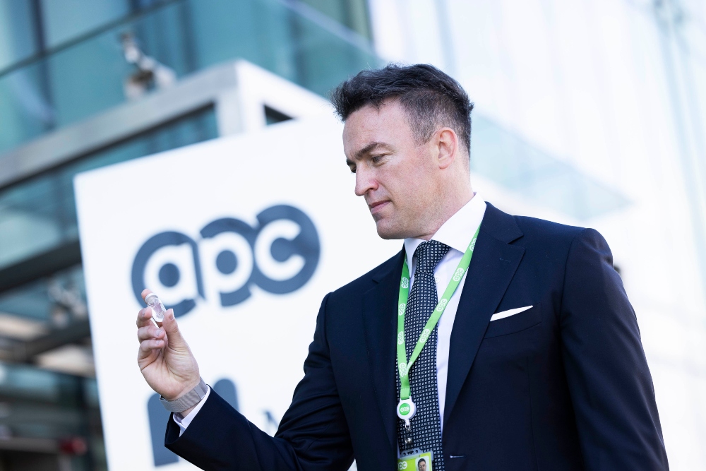 Man in suit holding vial of Covid vaccine.