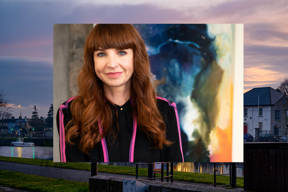 Auburn haired woman in black and pink dress.