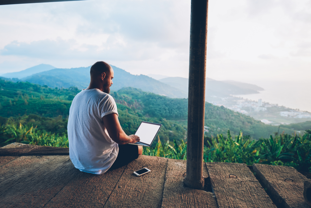 Man sitting on a veranda working on his computer.