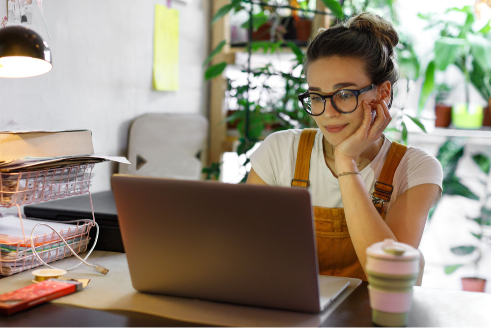 Woman in glasses working on laptop.