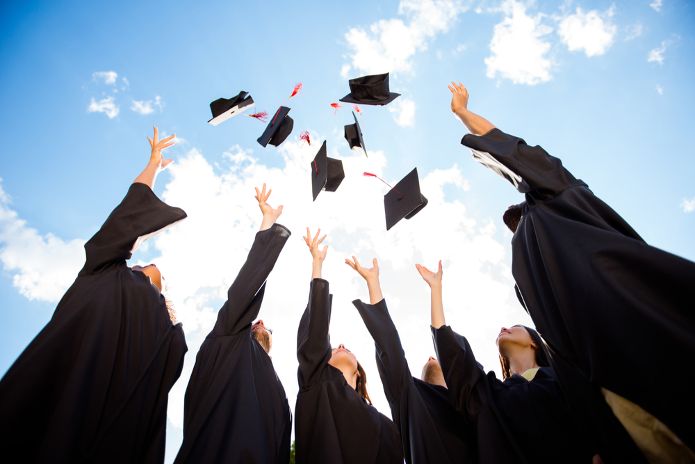 Graduates toss their hats in the air.