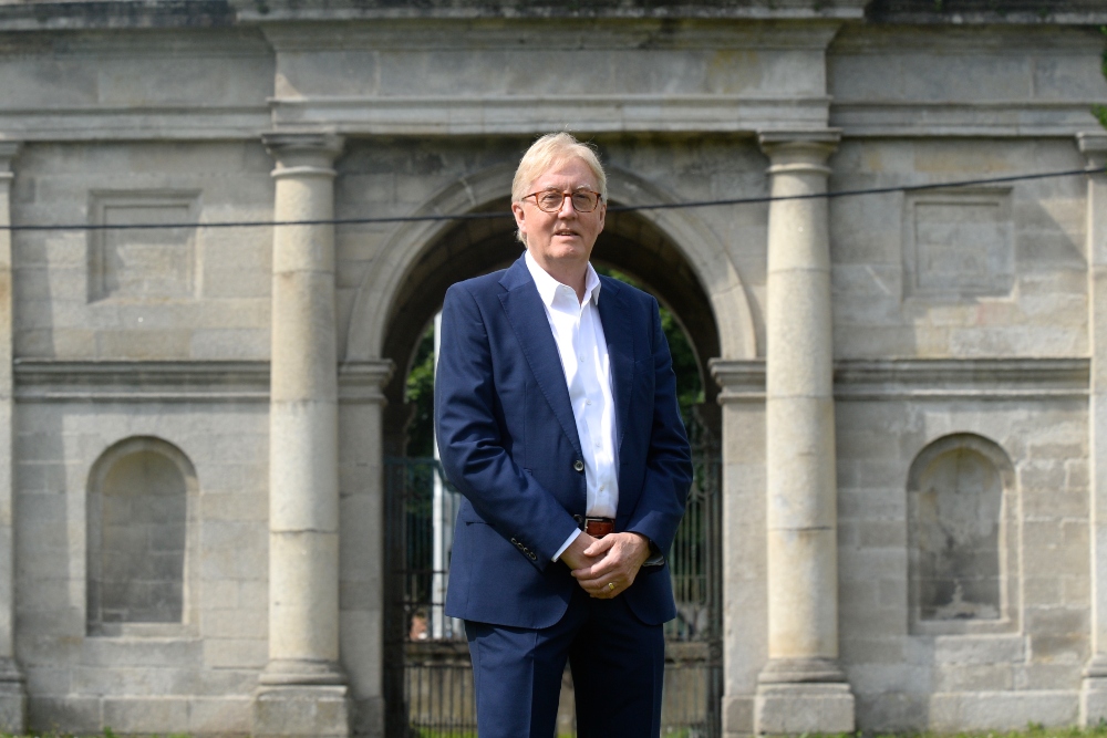 Man in blue suit standing in front of monument.