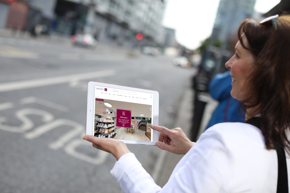 Woman holding a tablet with Kilkenny VR store.