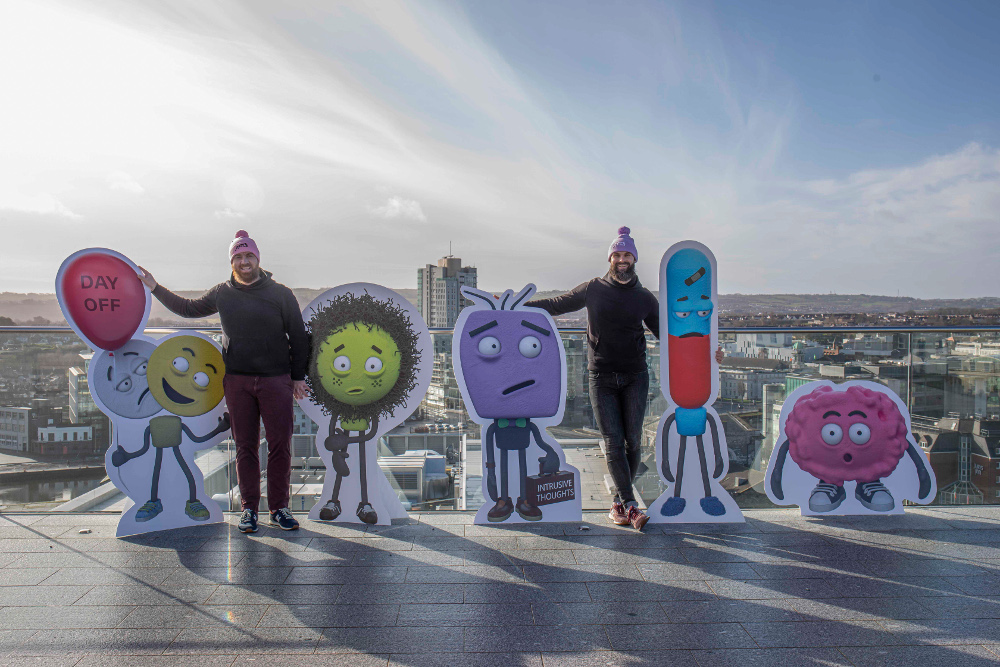 Two men on a rooftop in Cork with animated characters.