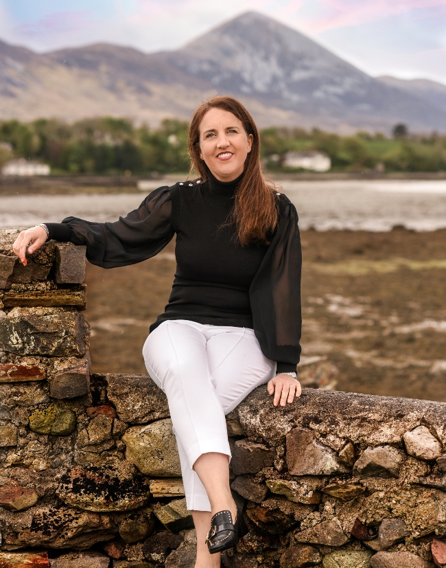 Dakr-haired woman sitting in a wall in Mayo.