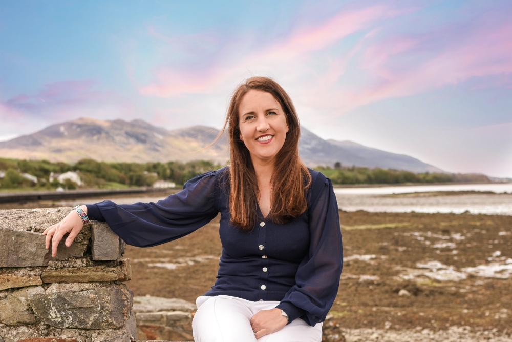 Dakr-haired woman sitting in a wall in Mayo.