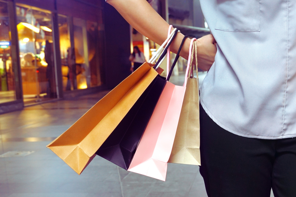 Woman hanging shopping bags in her hand and acting hands on waist.