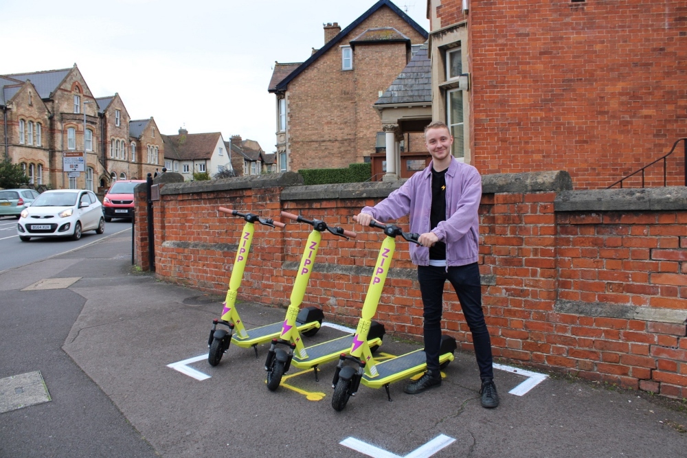 Man in purple jacket with yellow e-scooters.