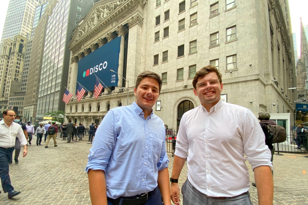 Two young men in front of the New York Stock Exchange.