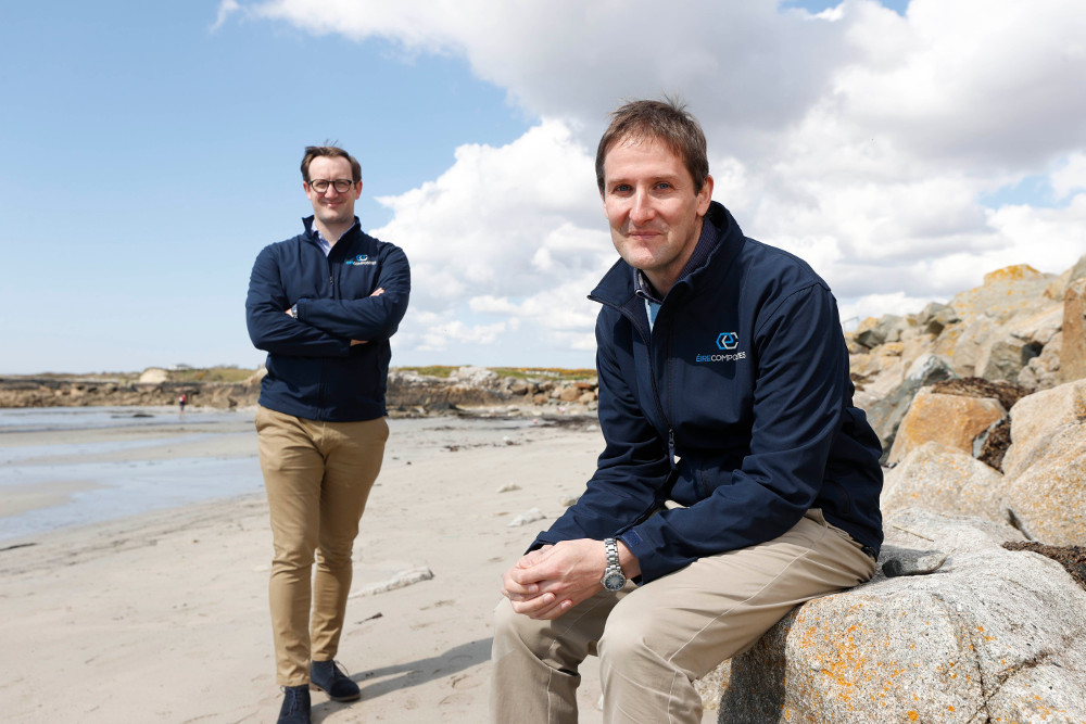 Two young men sitting on a beach.