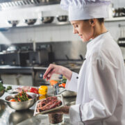 Chef preparing steaks in kitchen.