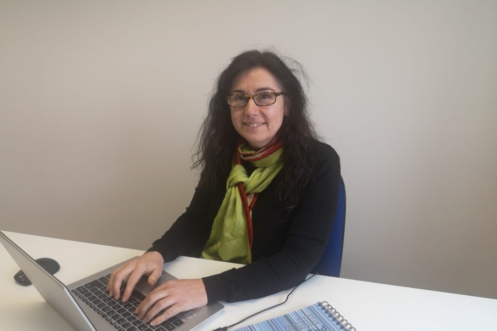 Woman wearing green scarf sitting at a computer.