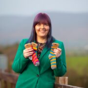 Woman in green jacket holding kids socks.