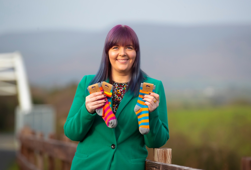 Woman in green jacket holding kids socks.