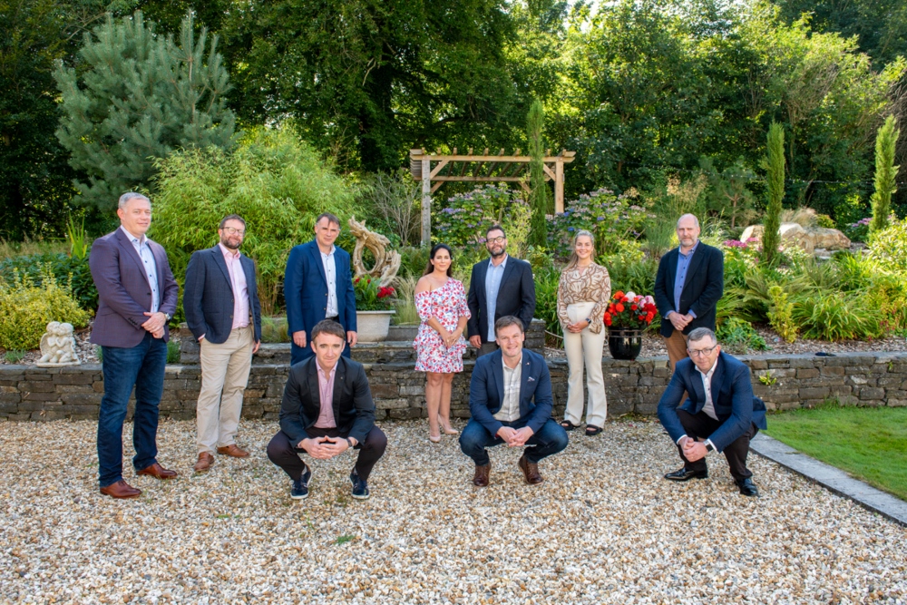 Group of men and women standing in a garden.
