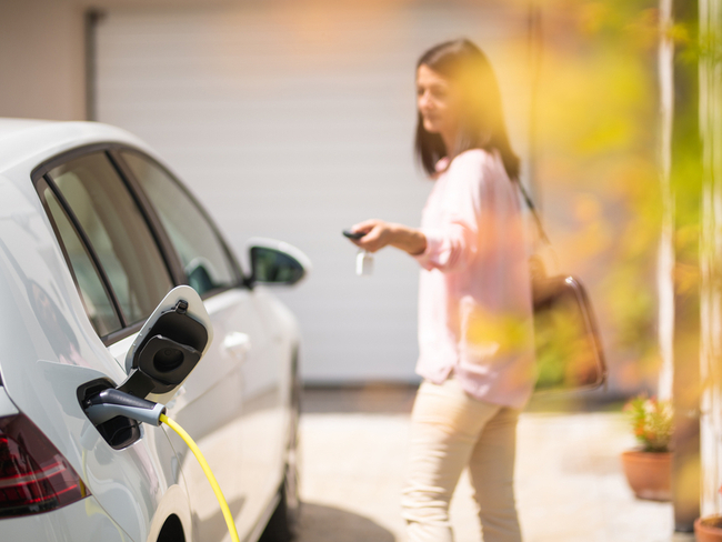 Woman locking electric car as it charges.